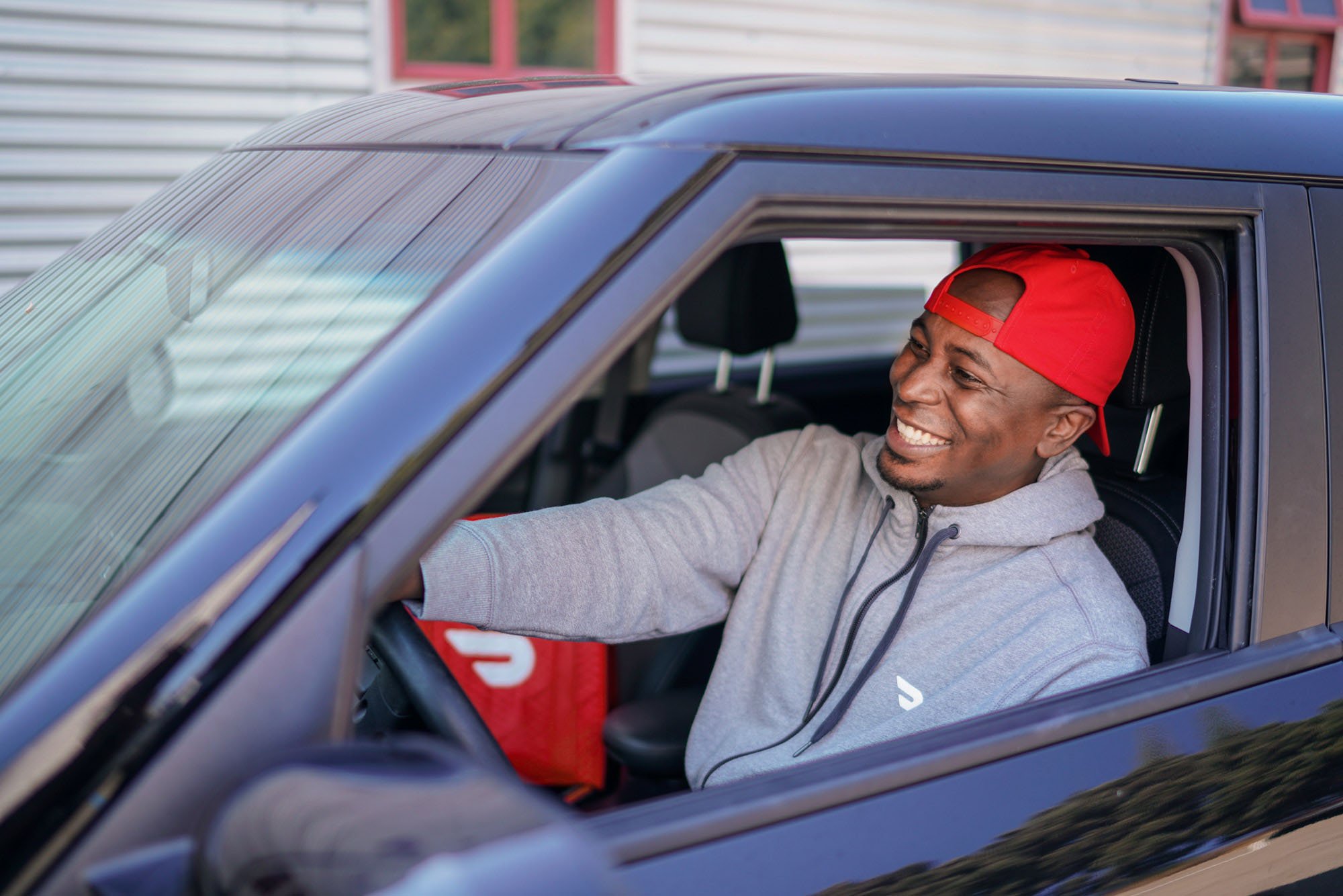DoorDash delivery driver smiling whilst driving with order