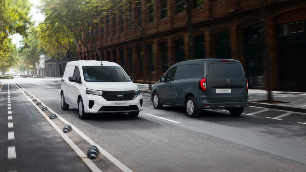 a white van and a dark grey van passing eachother on the road