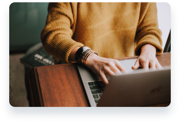 a person in a yellow jumper typing on a laptop