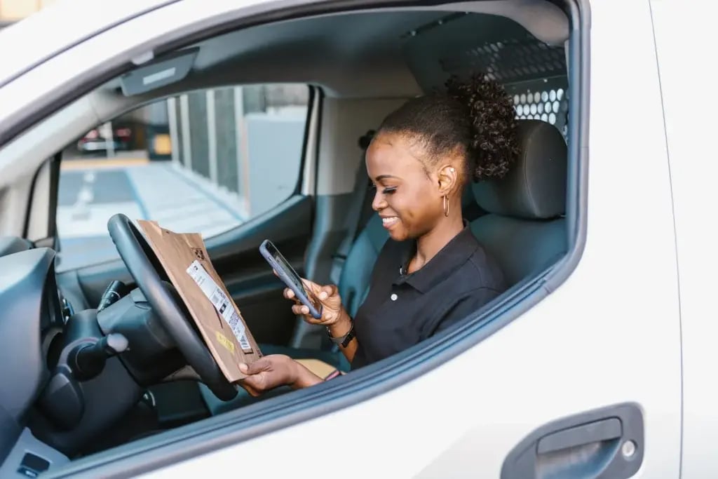 A woman in a white delivery van scanning a small parcel