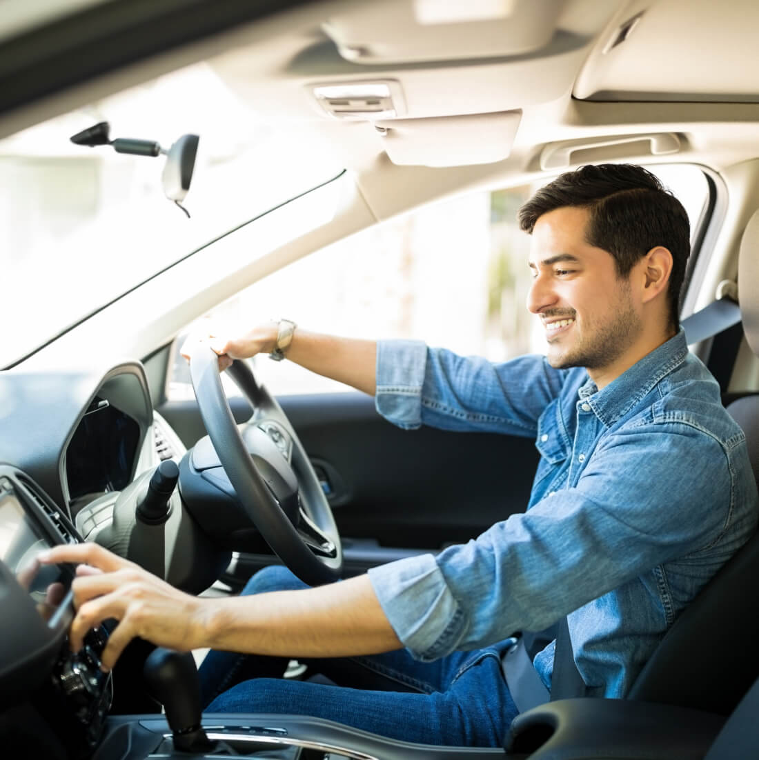 Man sitting in the driver's seat of his care, entering information into u keypad