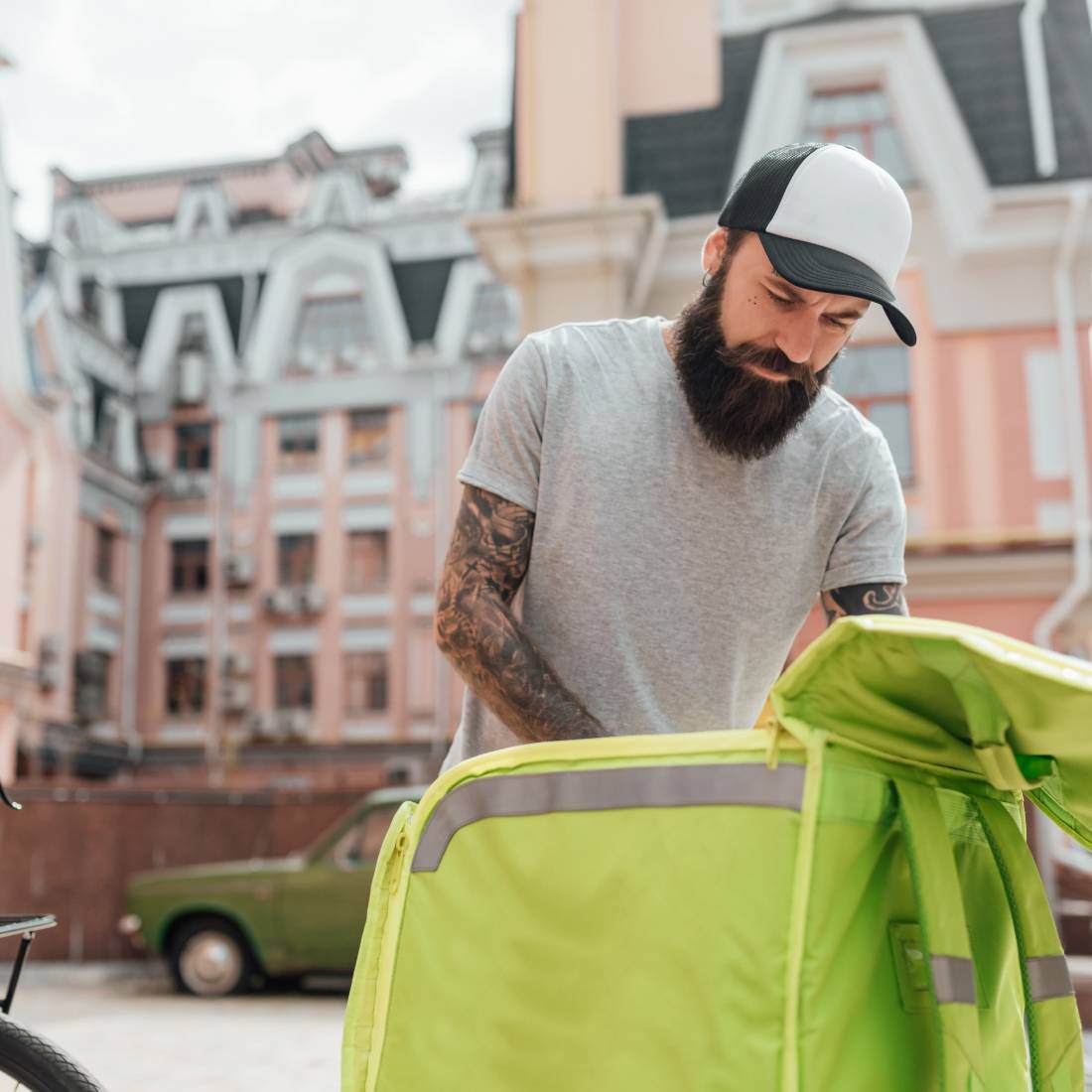 Delivery man in cap getting order out of a green bag