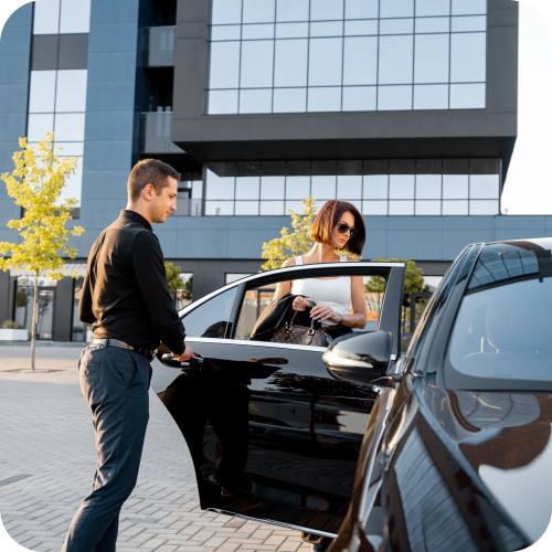 Male driver opening black car door for female passenger