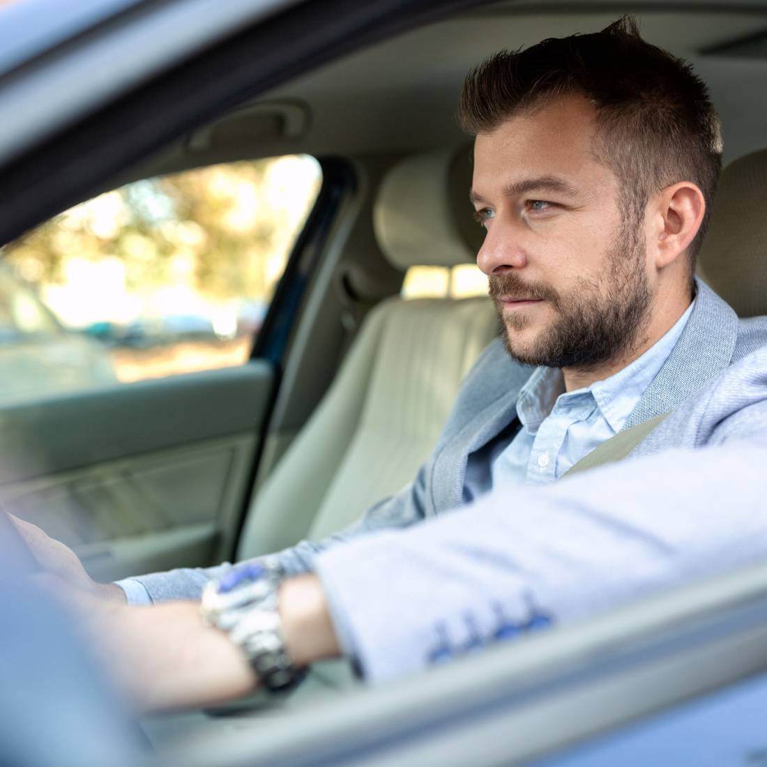 Man in a grey suit driving a car