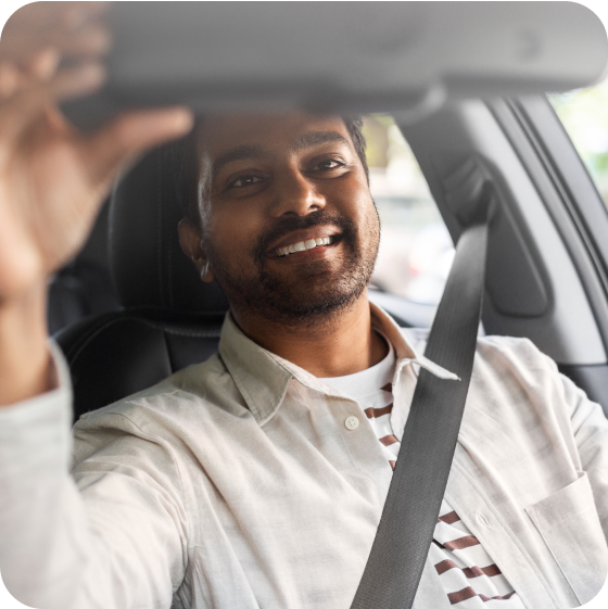 Man in car wearing a white jacket adjusting mirror