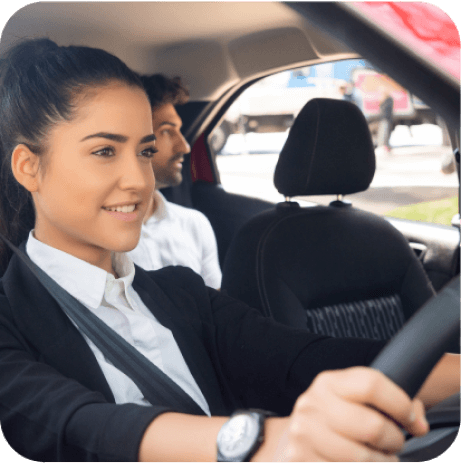 Woman in suit driving a car with a passenger in the back