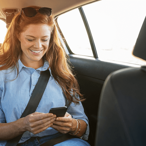 Smiling female passenger in a blue and white-striped shirt looking at her phone