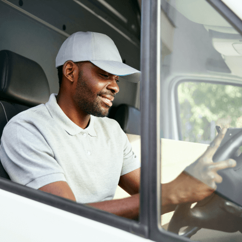 Man in white shirt and cap driving his van