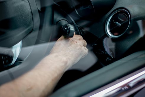 a hand turning the key in an ignition