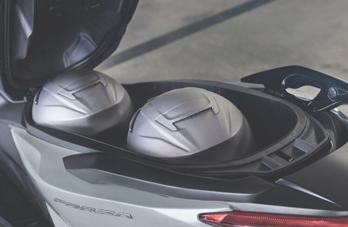 two silver motorcycle helmets in the storage box of a scooter or motorcycle