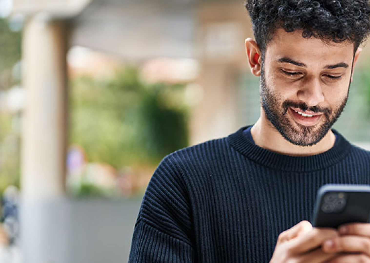 a man with dark curly hair looks at his phone