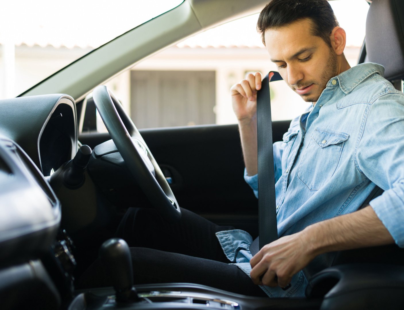 a man in a blue button shirt clicks in his seatbelt