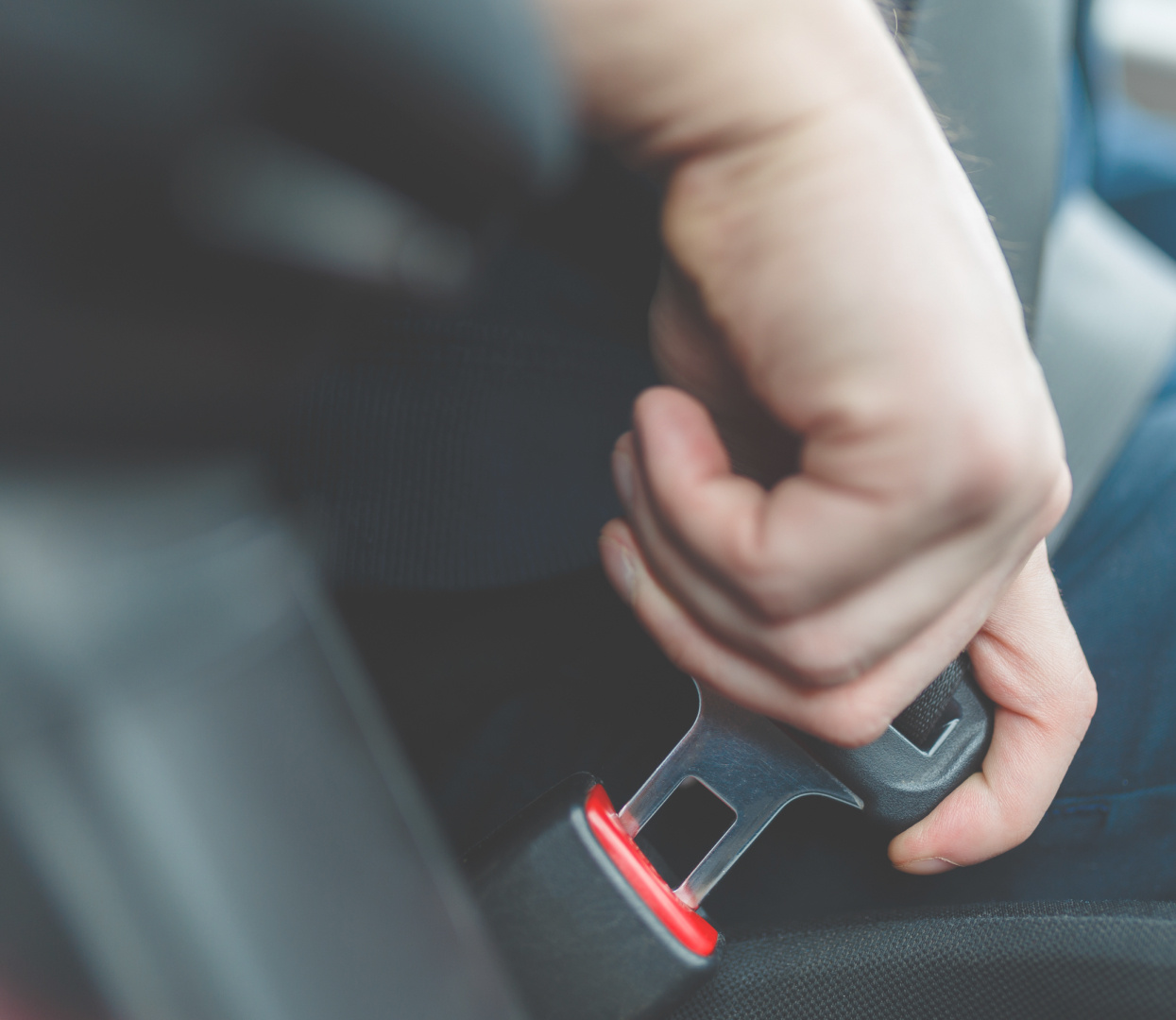 a person clicking in their seat belt in a vehicle