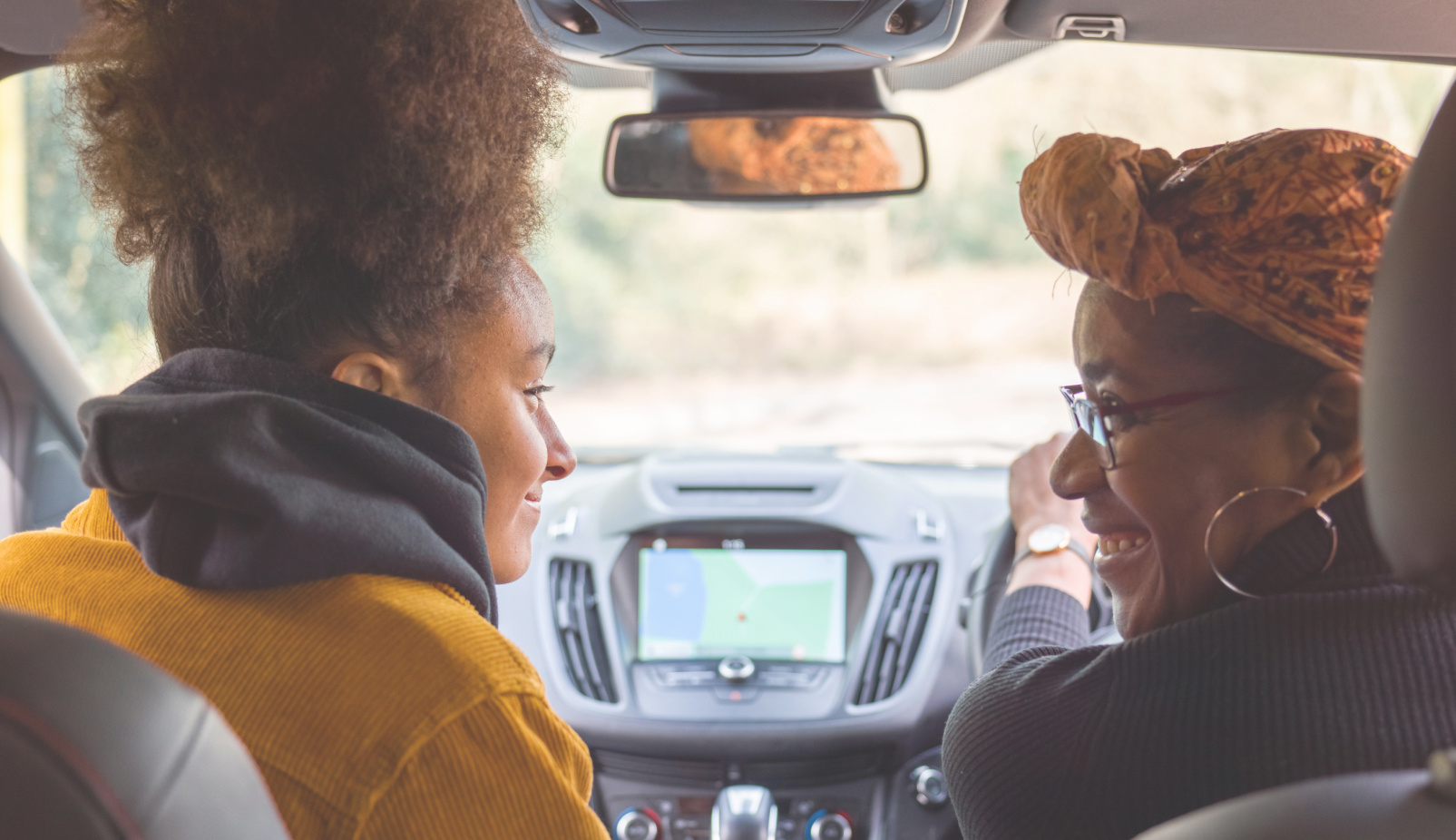 a female private hire driver in a headscarf smiles at her female passenger