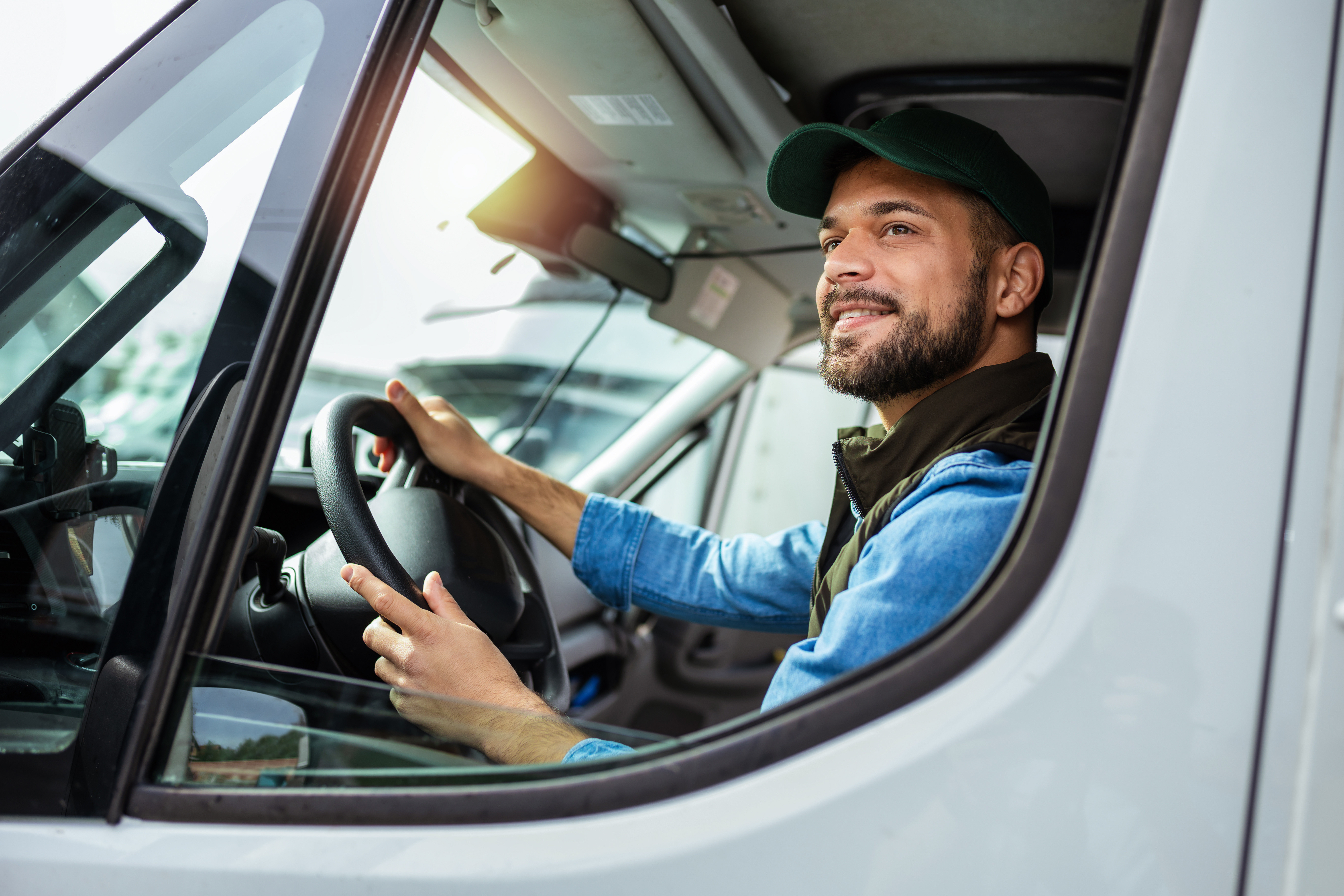 a man in a delivery driver uniform sits in the drivers seat of a vehicle