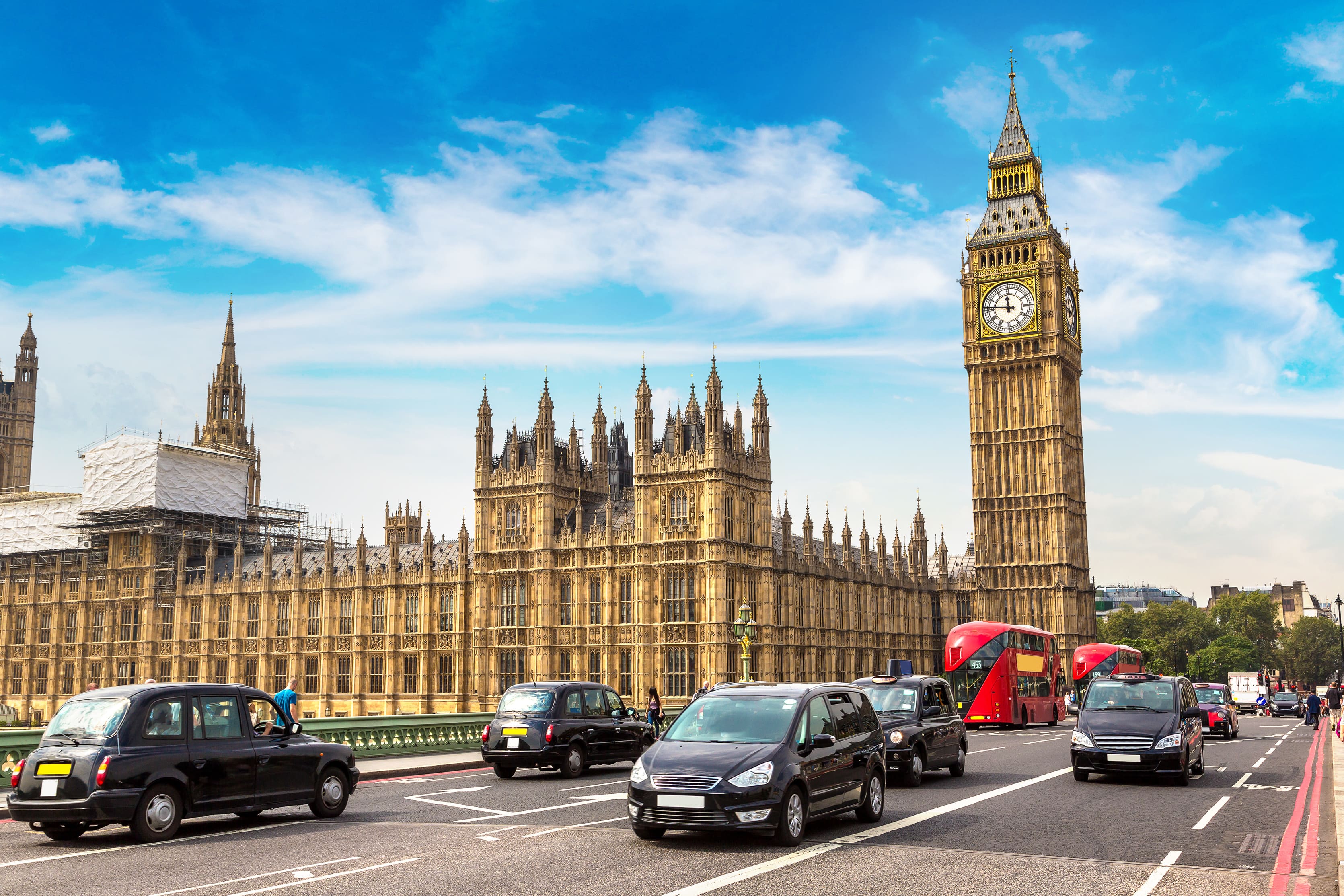 Black taxi cabs and private hire vehicles driving past the Houses of Parliament in London, representing the PHV VAT tax and Autumn Budget.