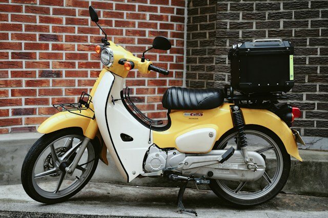 a yellow scooter parked by a brick wall