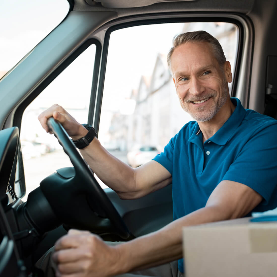 Man in blue shirt with hands on steering wheel and gear stick