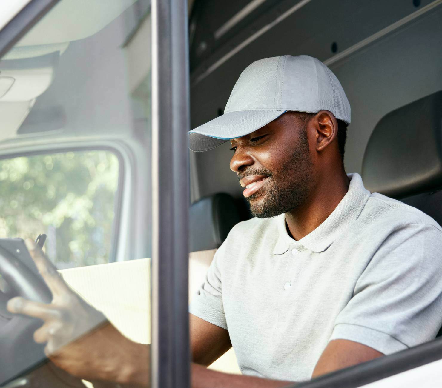 Man with cap in van writing on clipboard