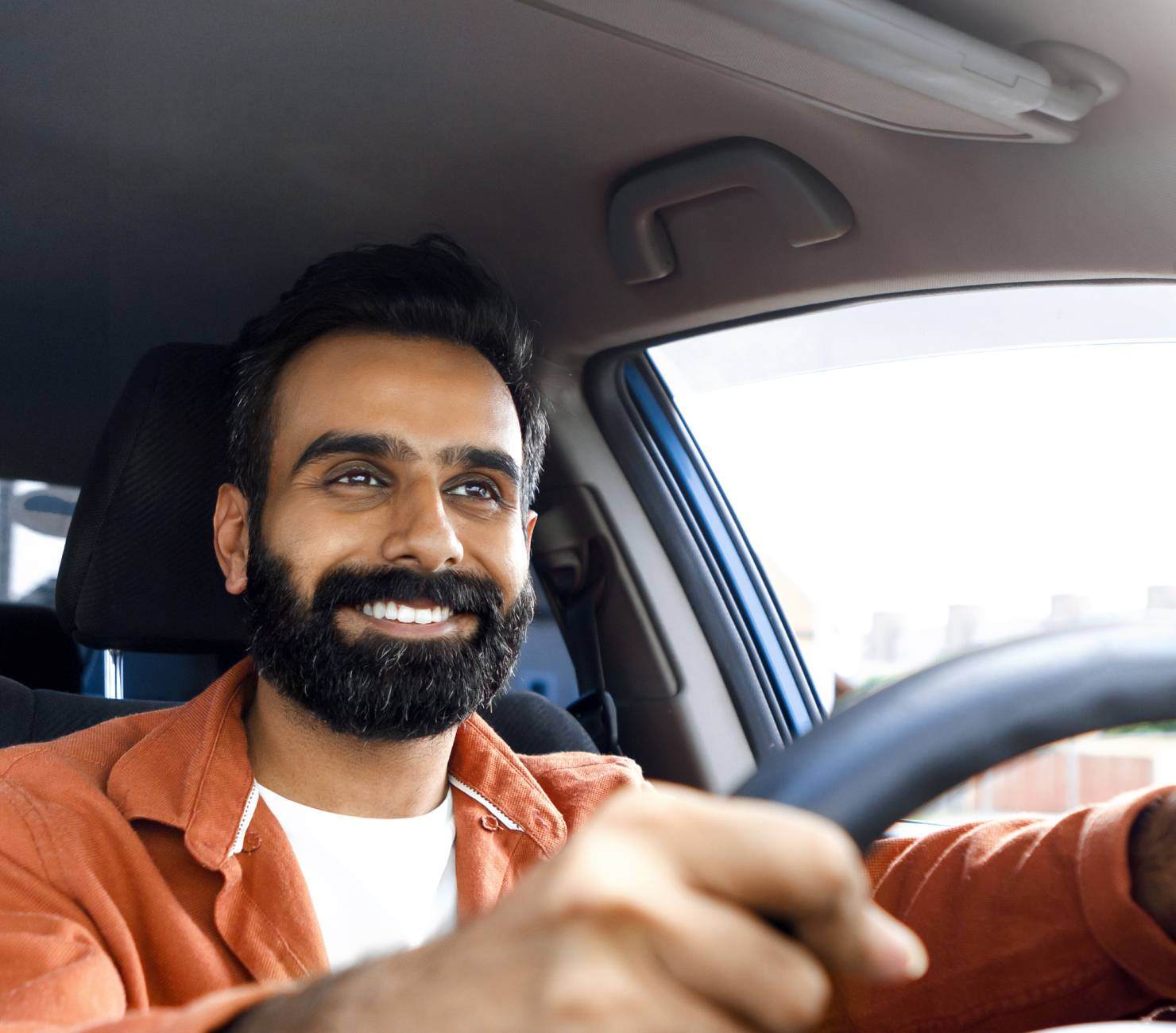 Man in an orange jacket driving car