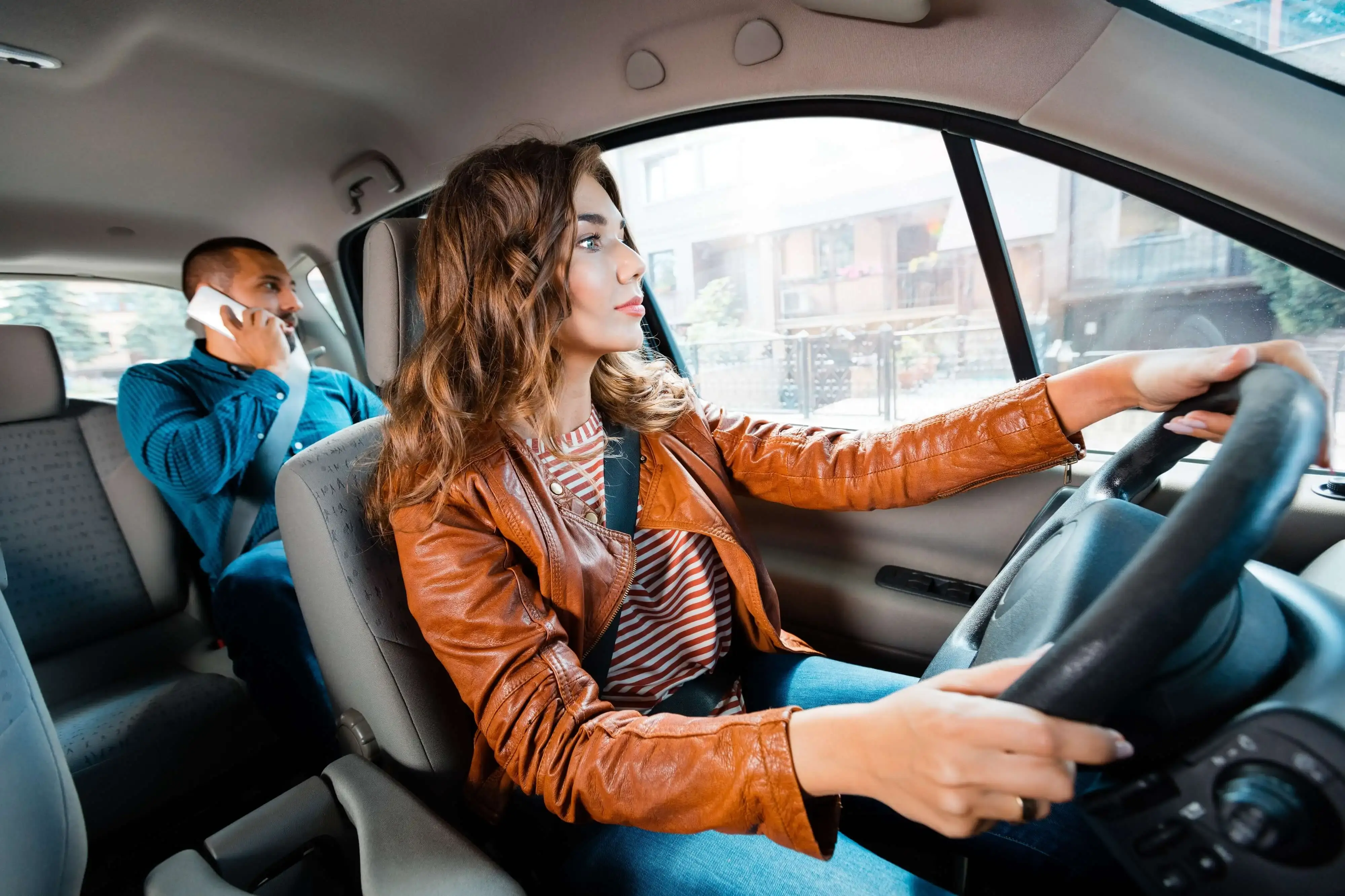 Taxi driver in a brown leather jacket with passenger talking on his phone