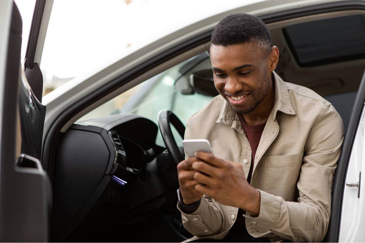 Man getting out of car looking at phone