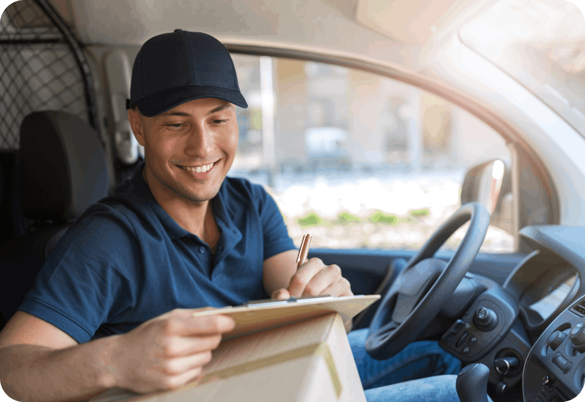 Man with cap writing on clipboard in van