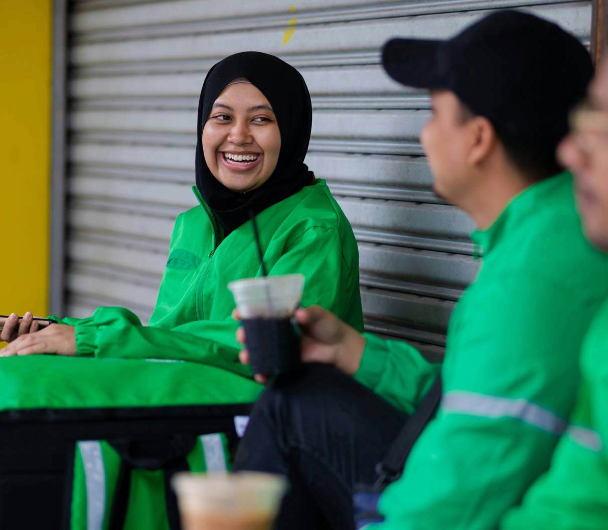 Team of drivers in green high-vis jackets talking and smiling