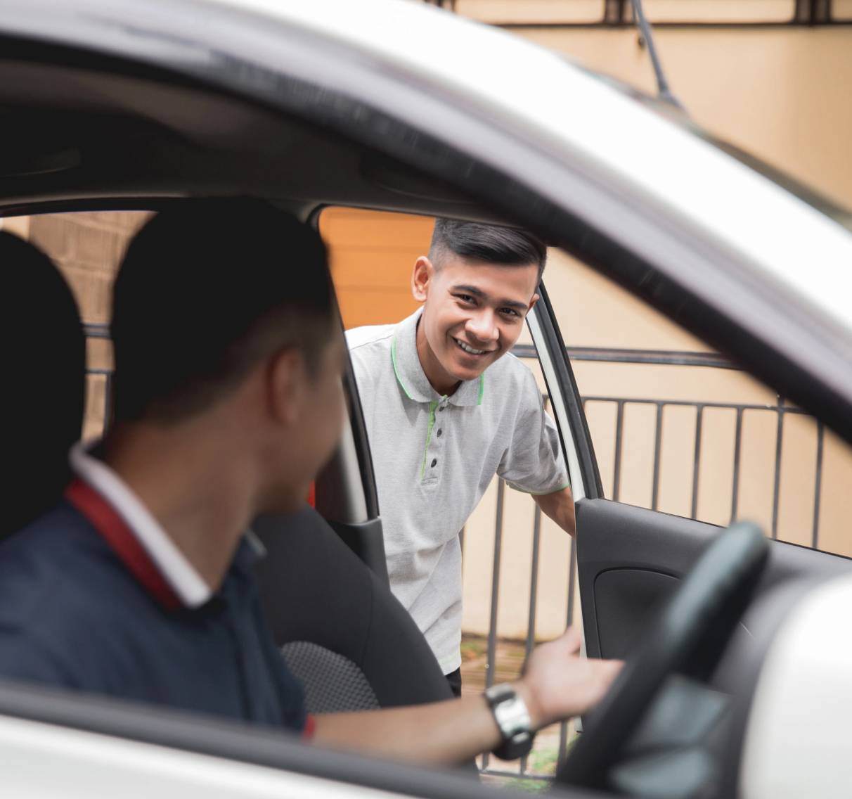 Young passenger talking to a taxi driver through the passenger-side door