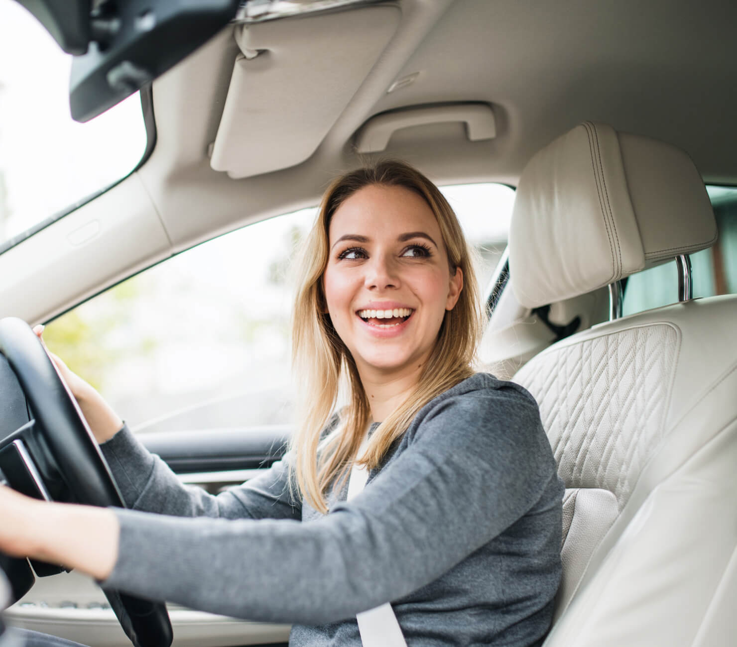 Woman in a grey top driving car looking to side