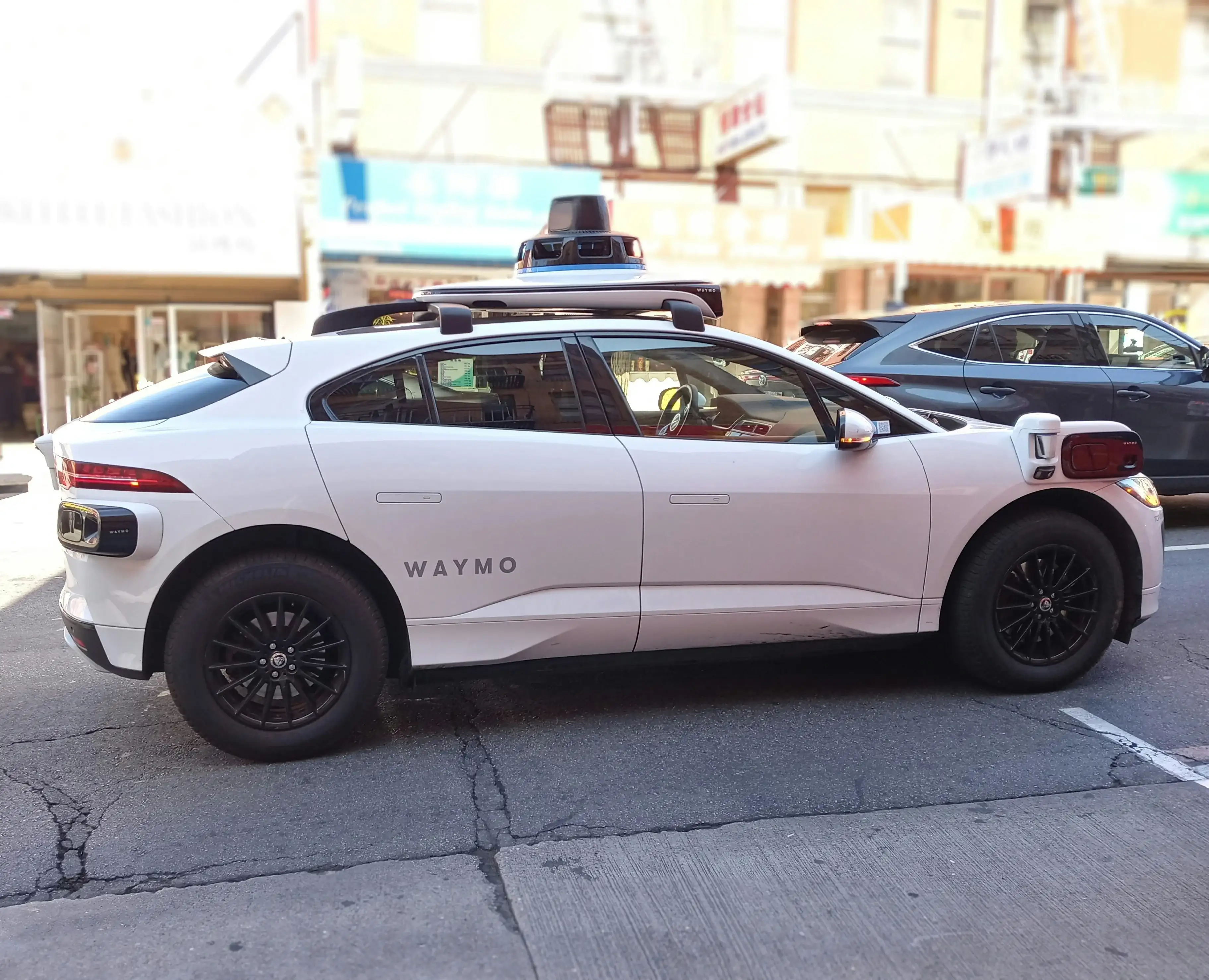White waymo driverless taxi on the street