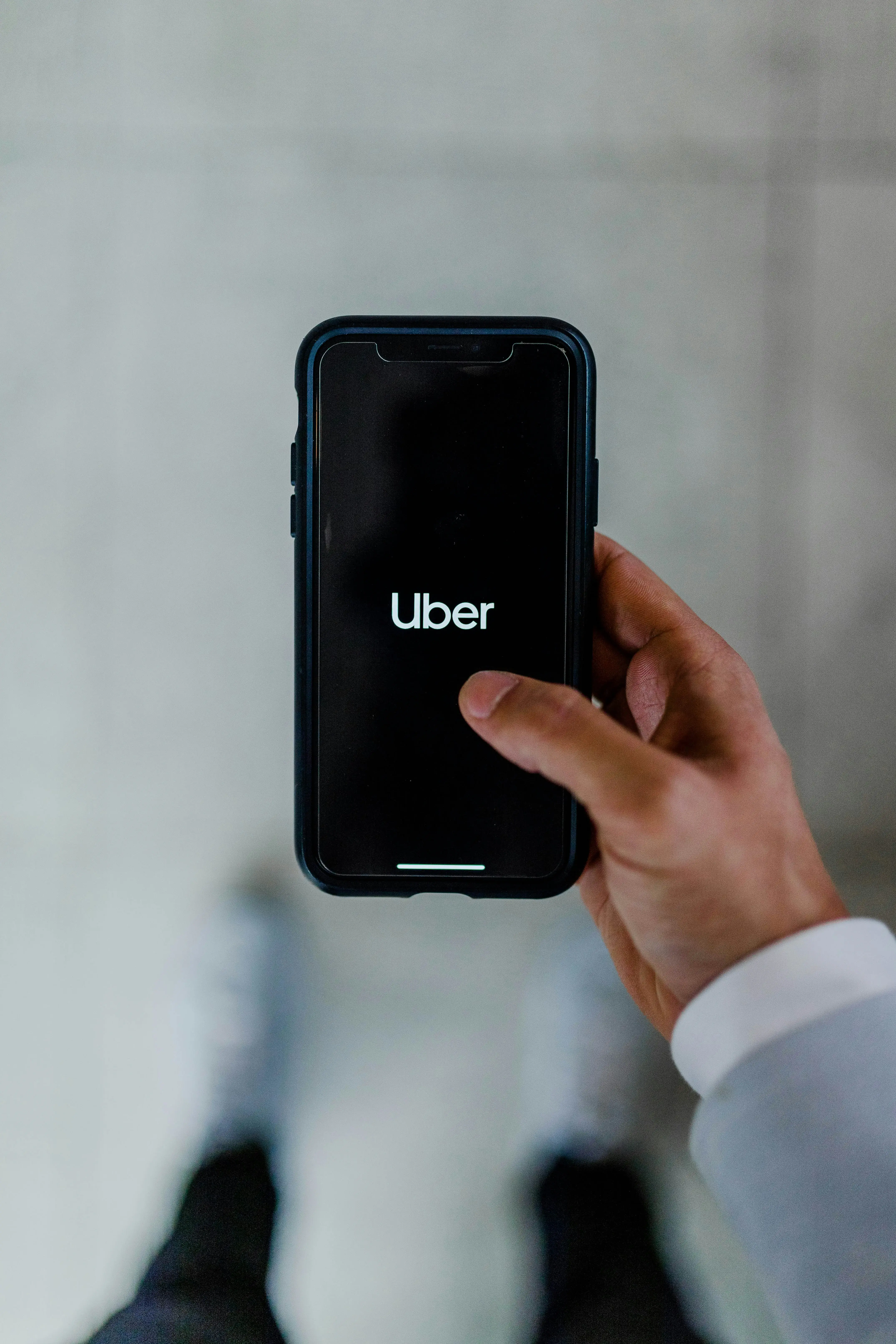 a person holding up a phone with the Uber logo on the screen