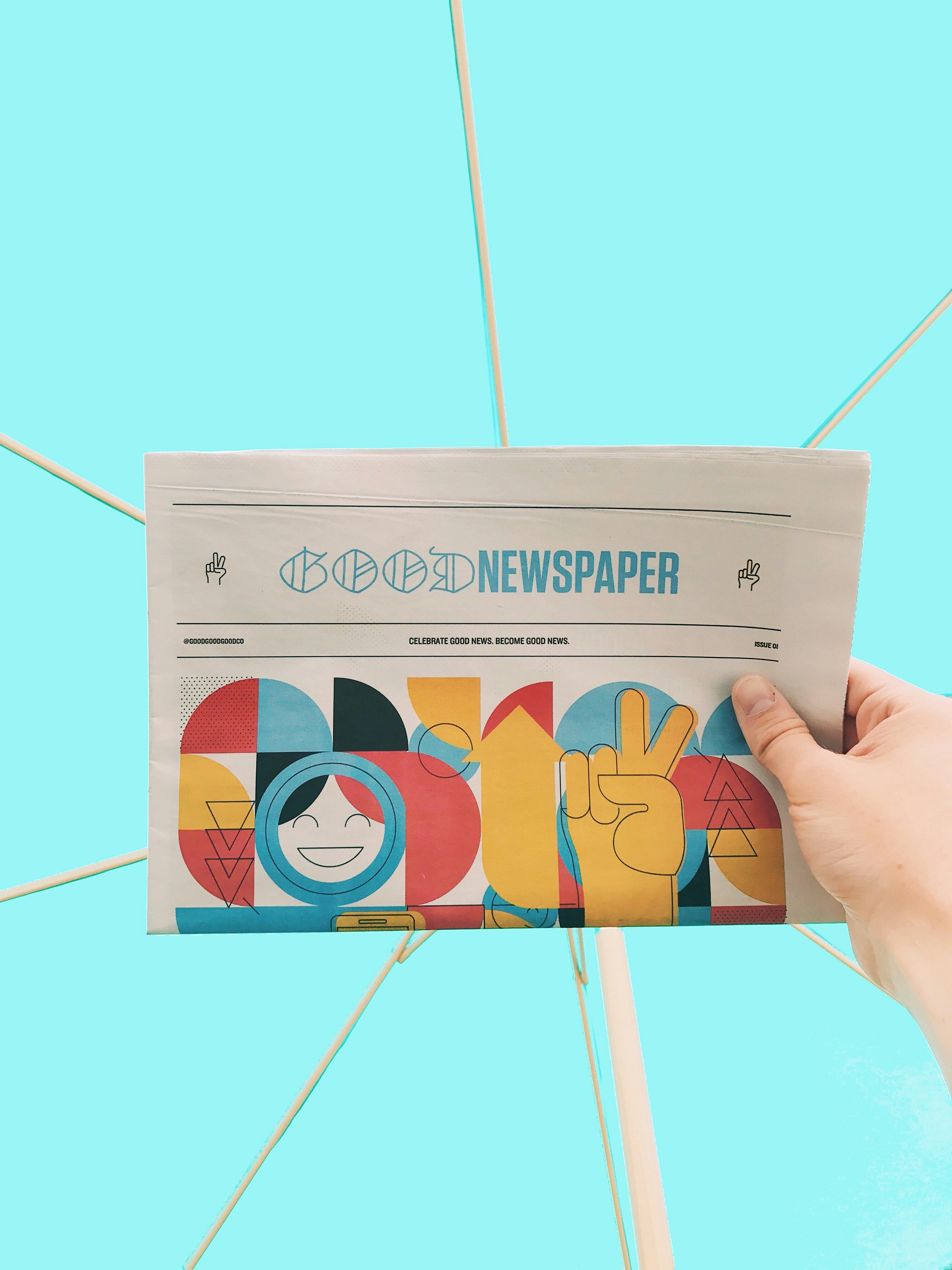 a hand holding a newspaper on a bright blue background