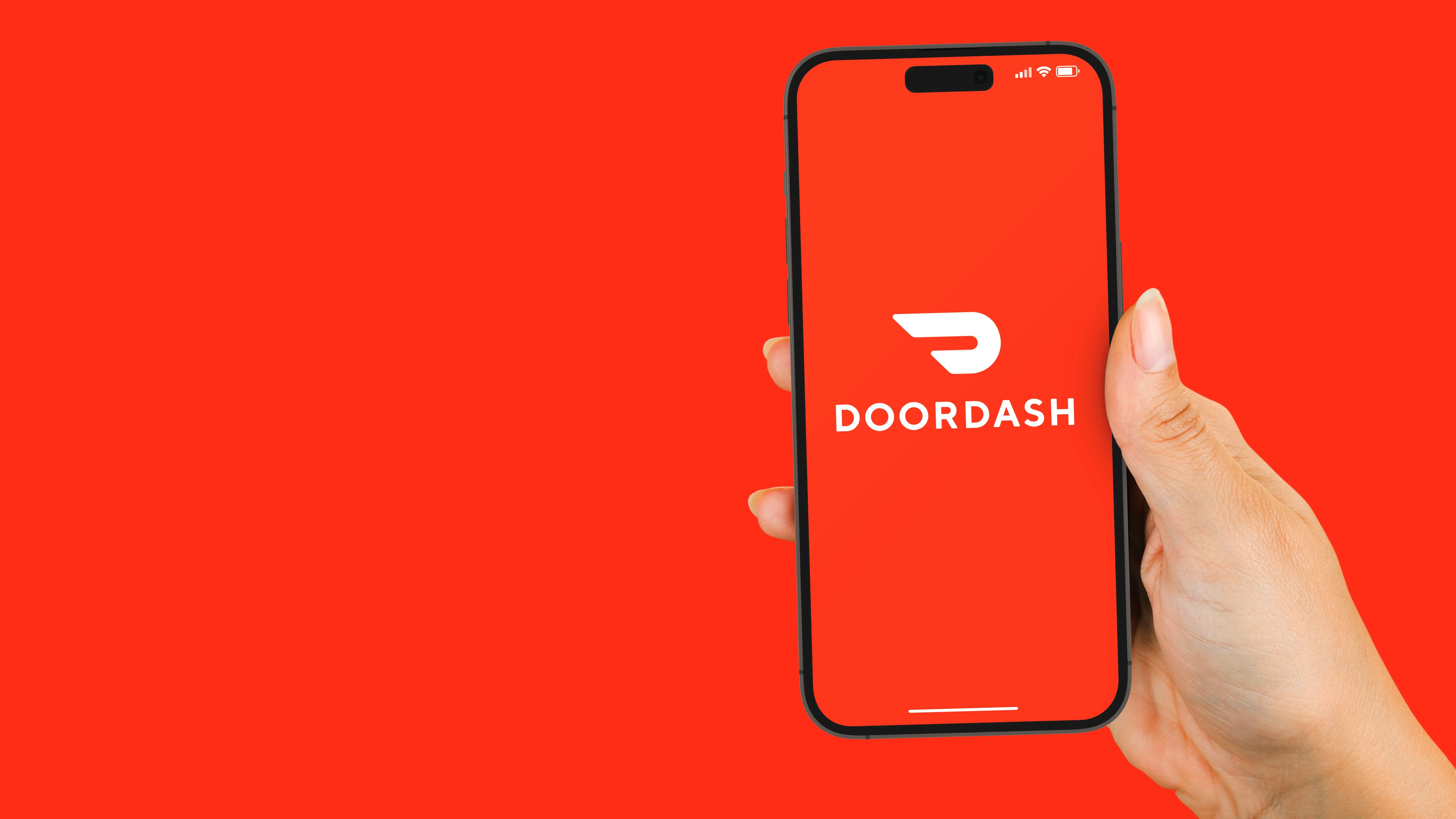 person holding phone displaying doordash app against a red background - doordash take over deliveroo