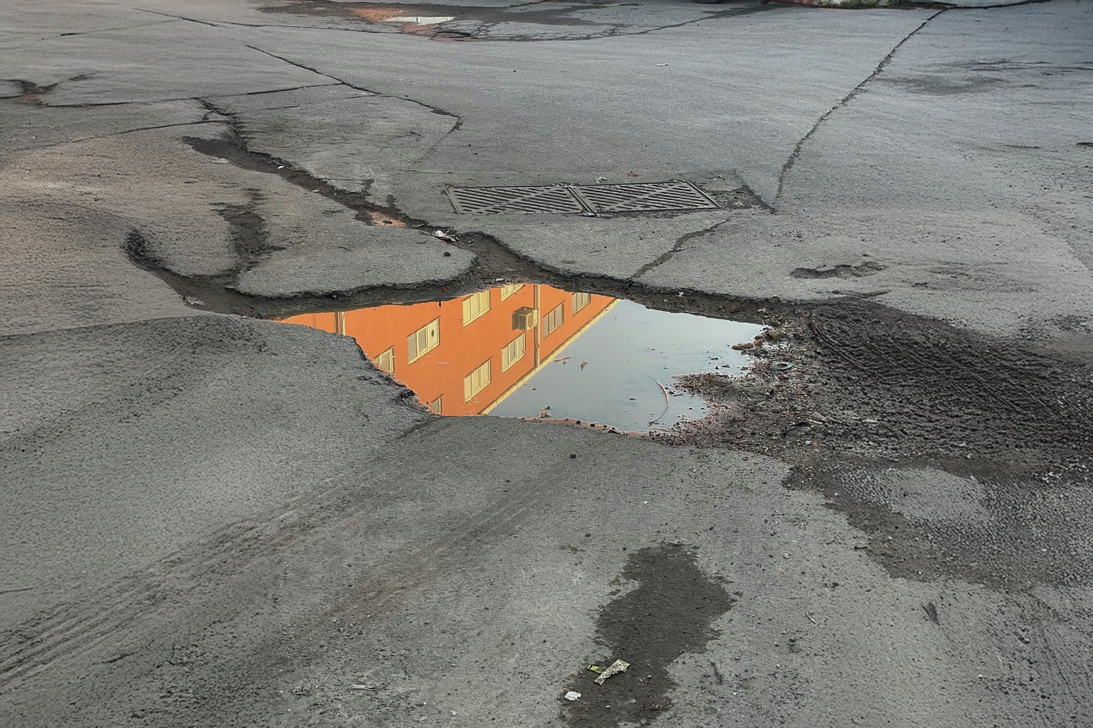 reflection of a building in standing water trapped in a large pothole