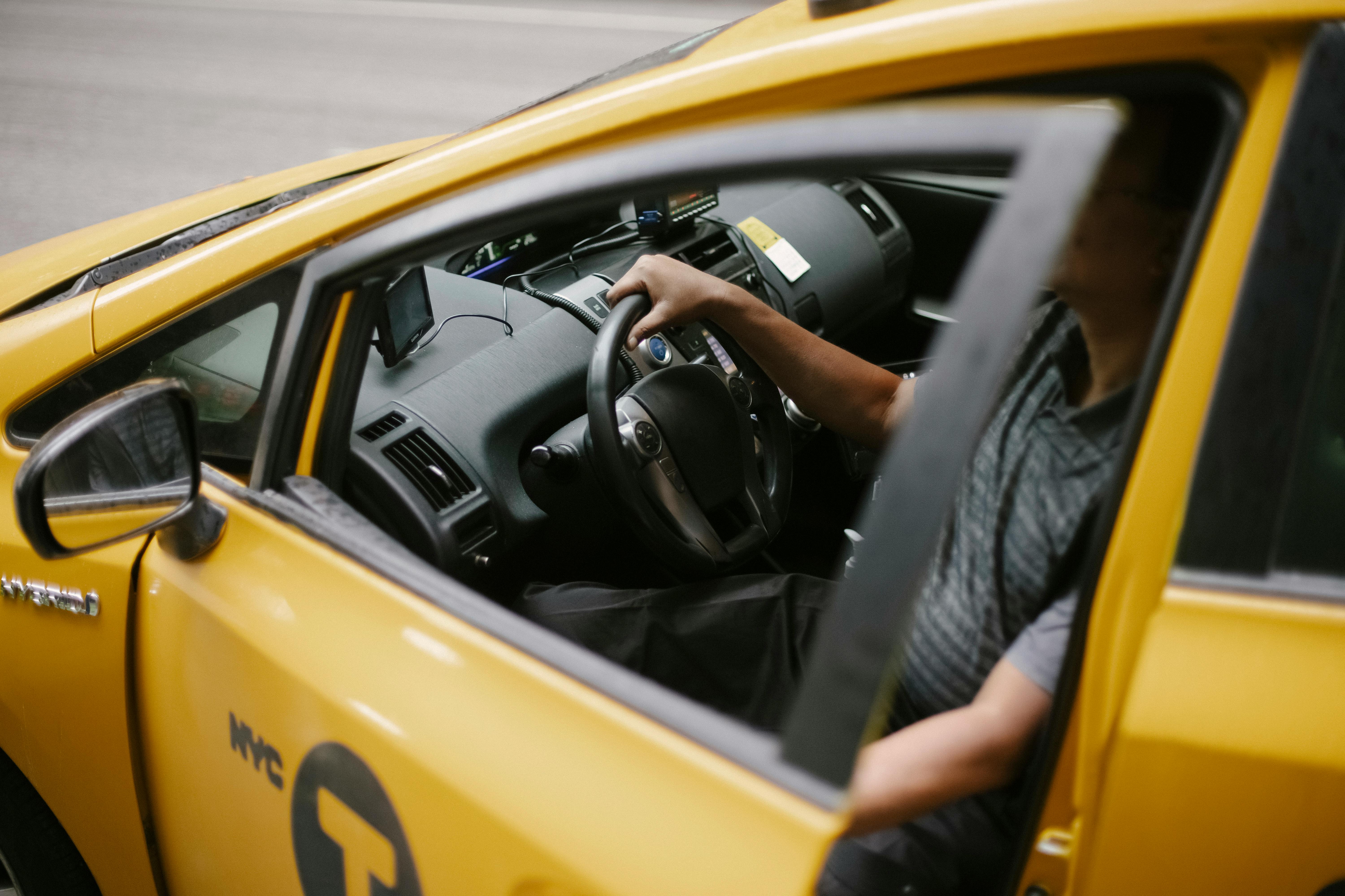 drivers side window of a yellow new york taxi cab