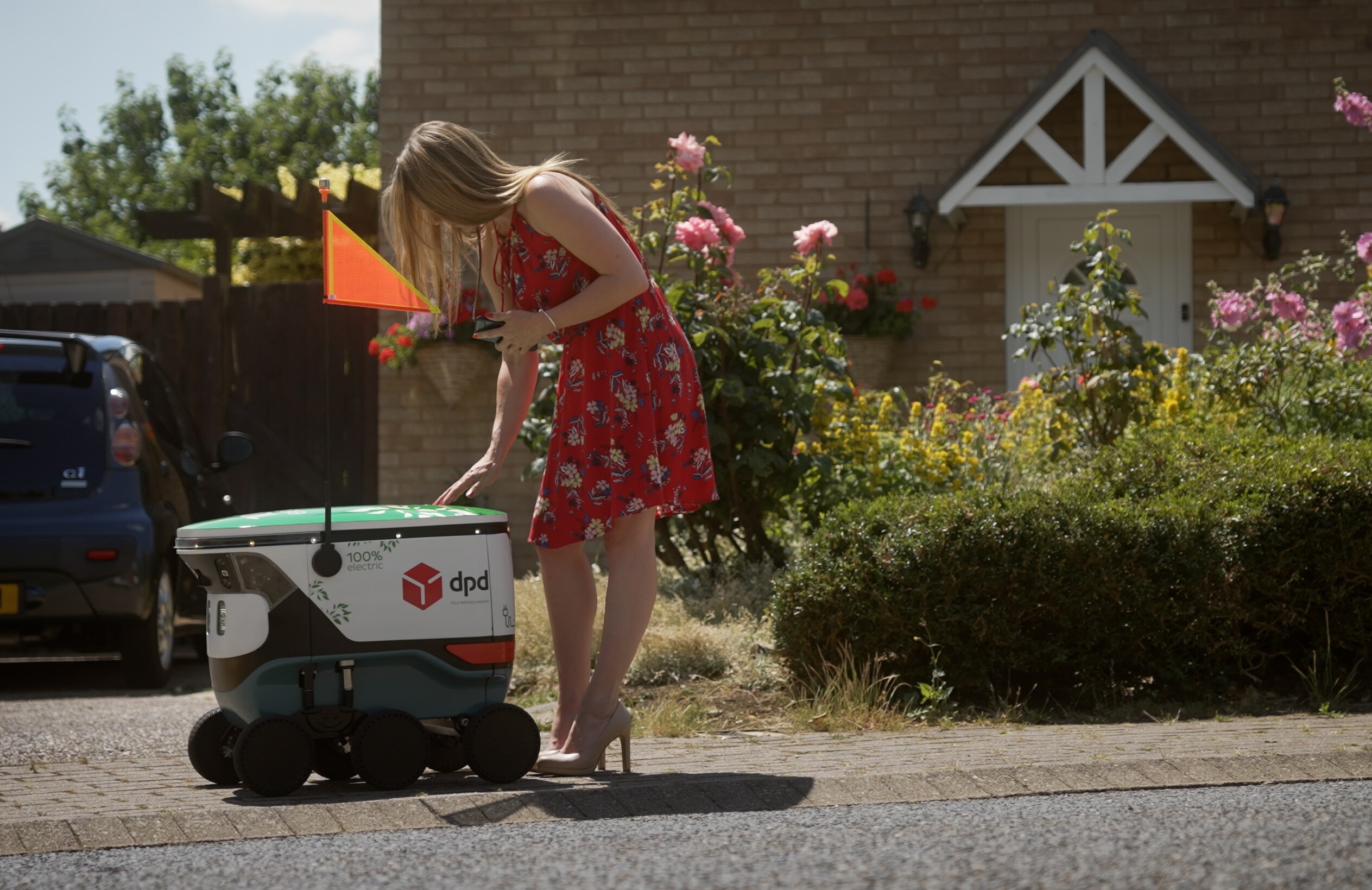 a woman in a red dress approaches a delivery robot