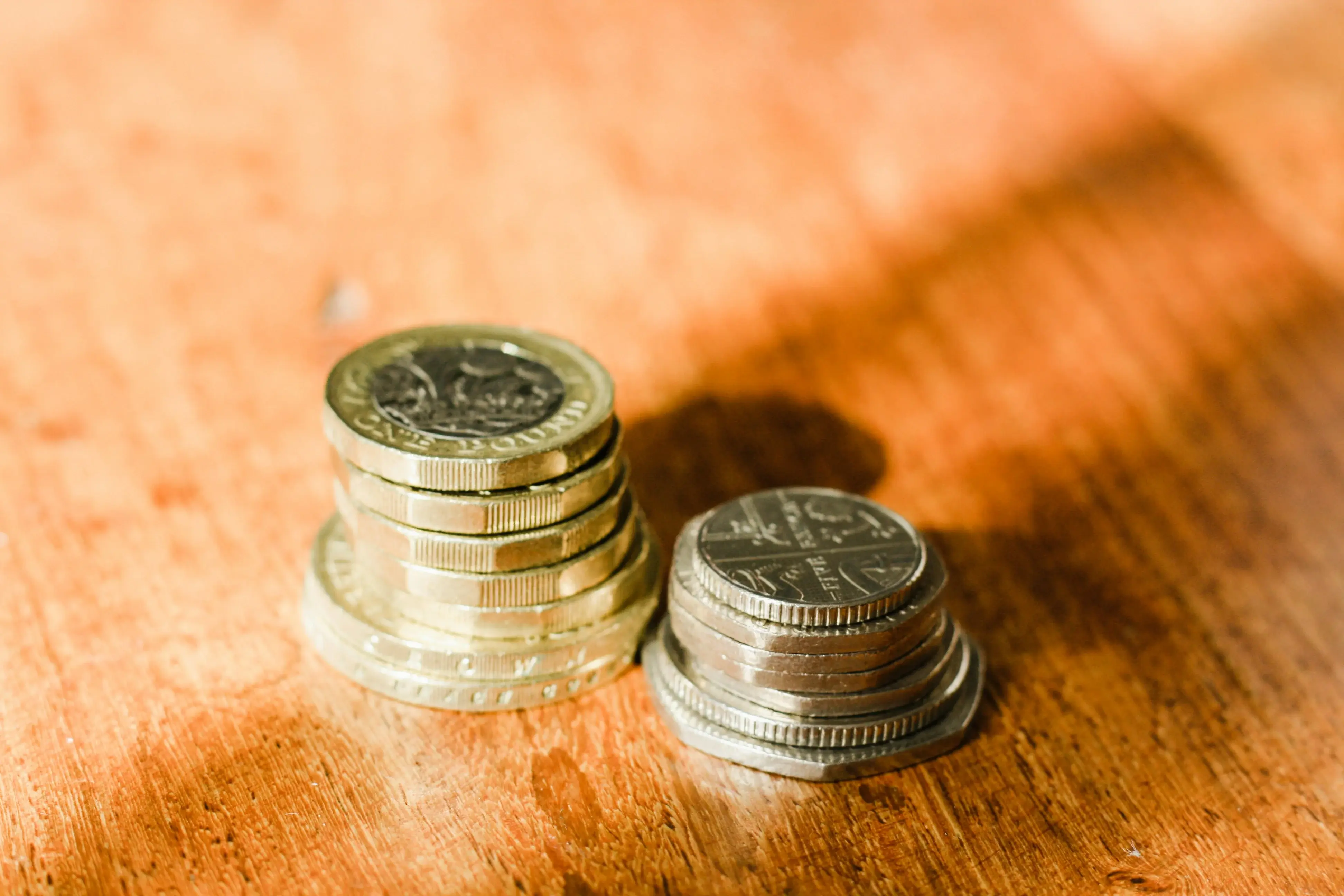 Two piles of british coins on a wooden tabletop