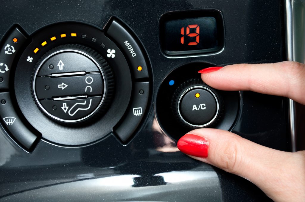 Person with red nail polish turns on air conditioning in a car