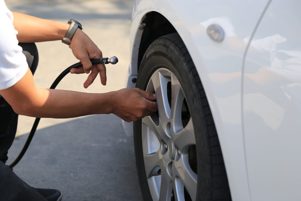 Close-up of car mechanic working and pumping air into auto wheel in auto repair service
