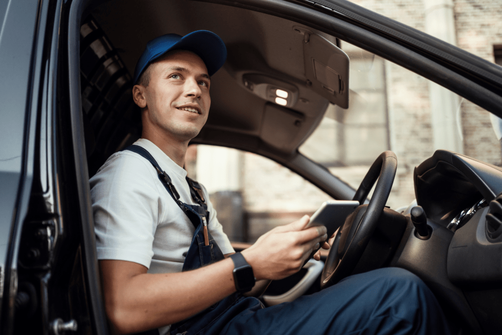 A man in a white shirt and a blue cap sat in the drivers seat of a van