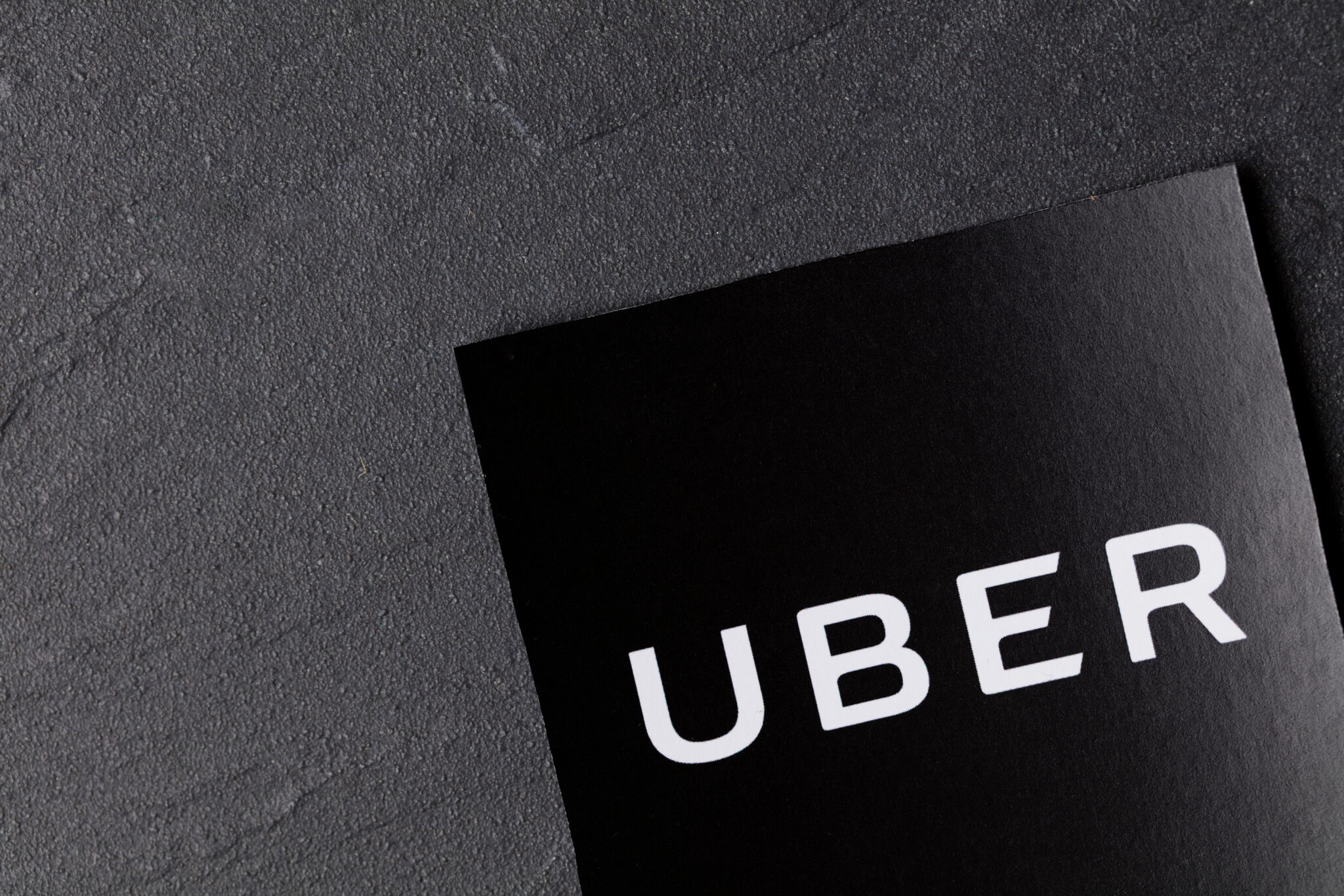 A photograph of the Uber logo. Uber is a popular taxi style transport service application, founded in 2009